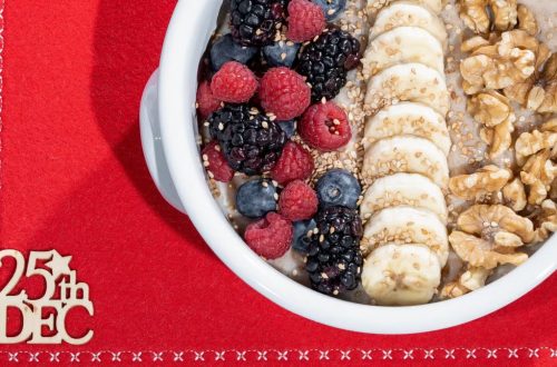 Delicious breakfast bowl with fresh fruits and nuts on a red holiday setting.