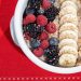 Delicious breakfast bowl with fresh fruits and nuts on a red holiday setting.